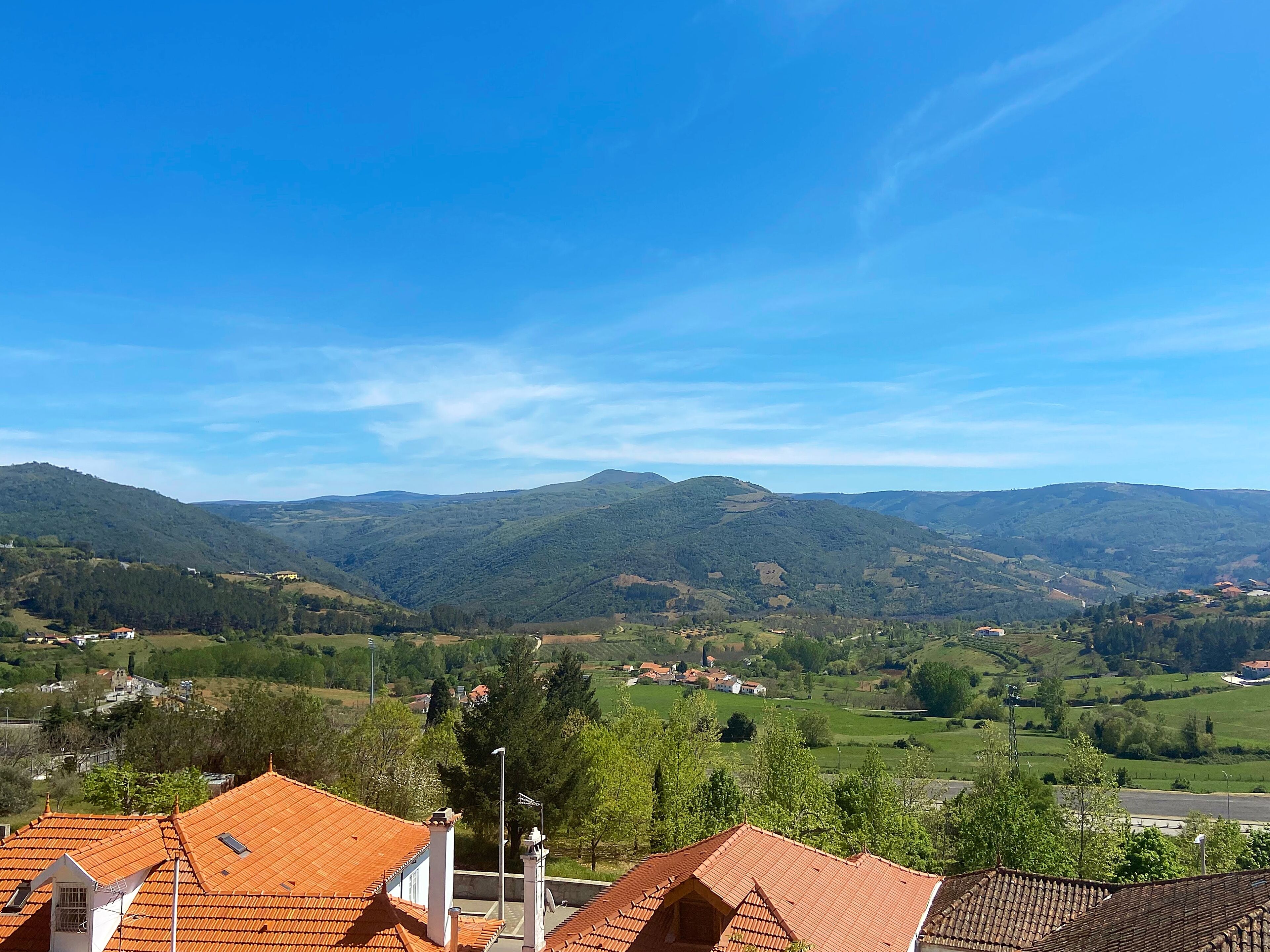 A view of a valley with green hills and a clear blue sky.