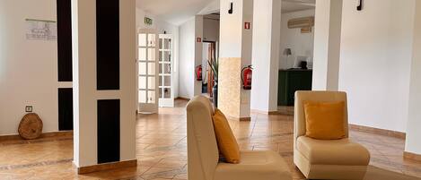 A spacious lobby with a beige sofa, a round rug, and a tiled floor.