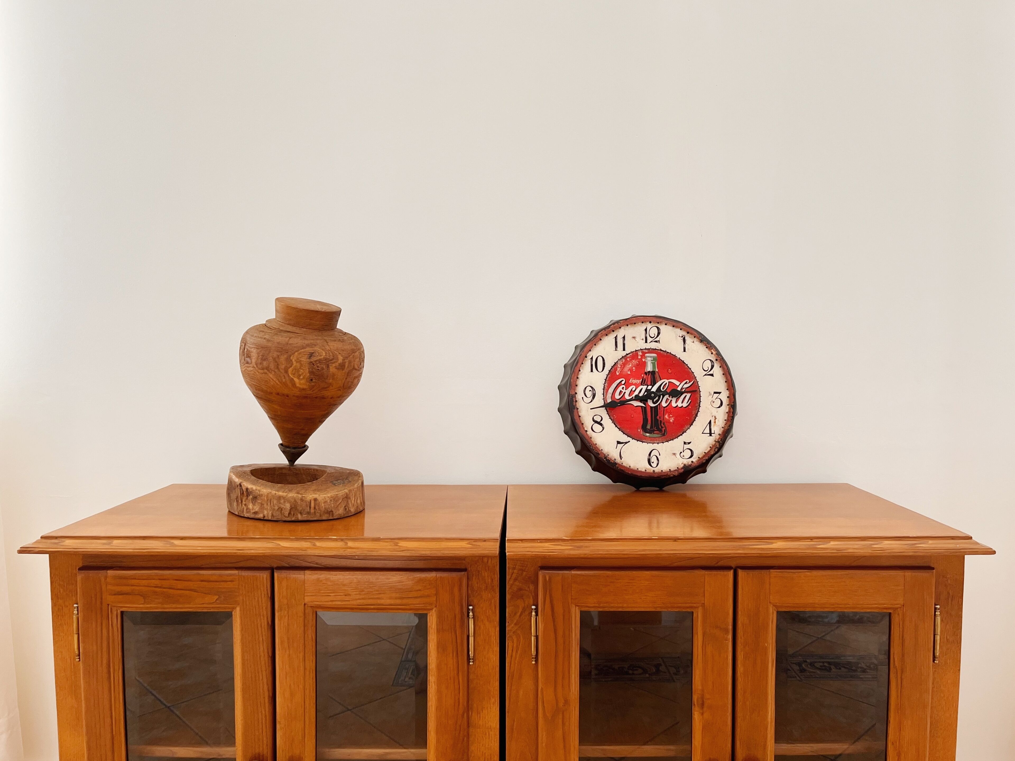 Un meuble en bois doté de portes en verre et surmonté d’une horloge à l’effigie de Coca-Cola.