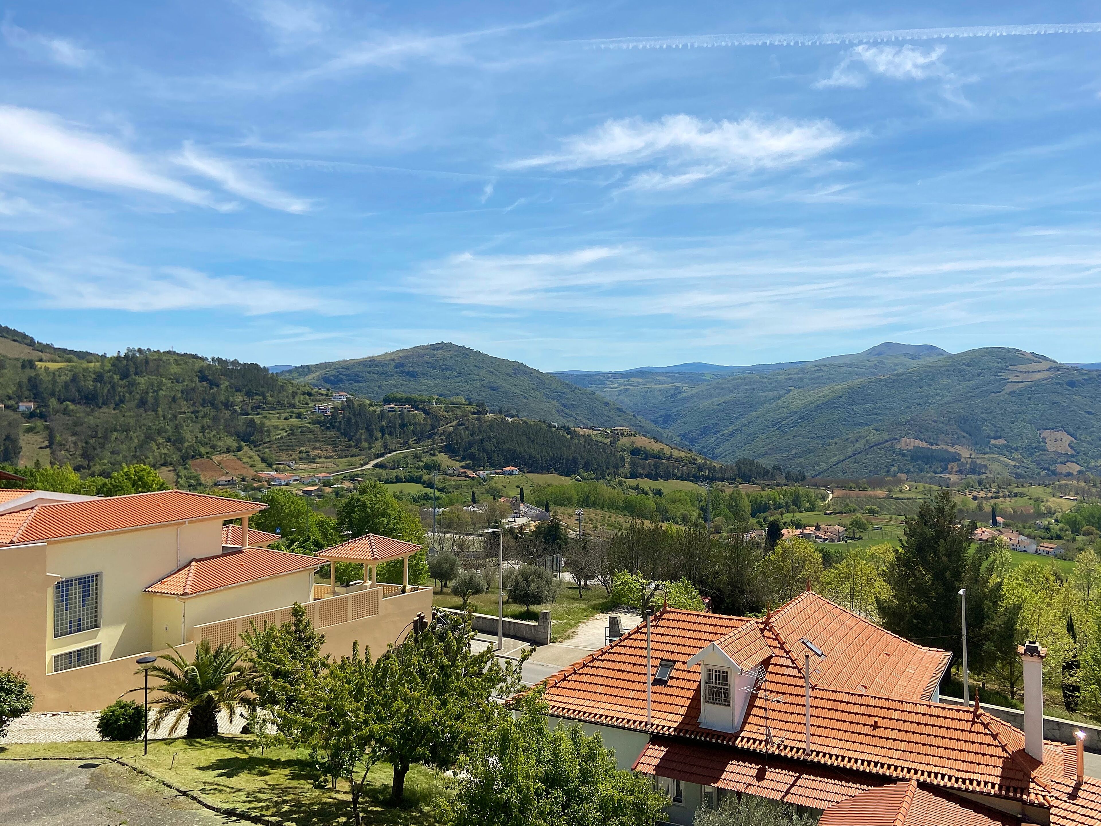 A residential area with terraced houses, a clear sky, and rolling hills in the background.