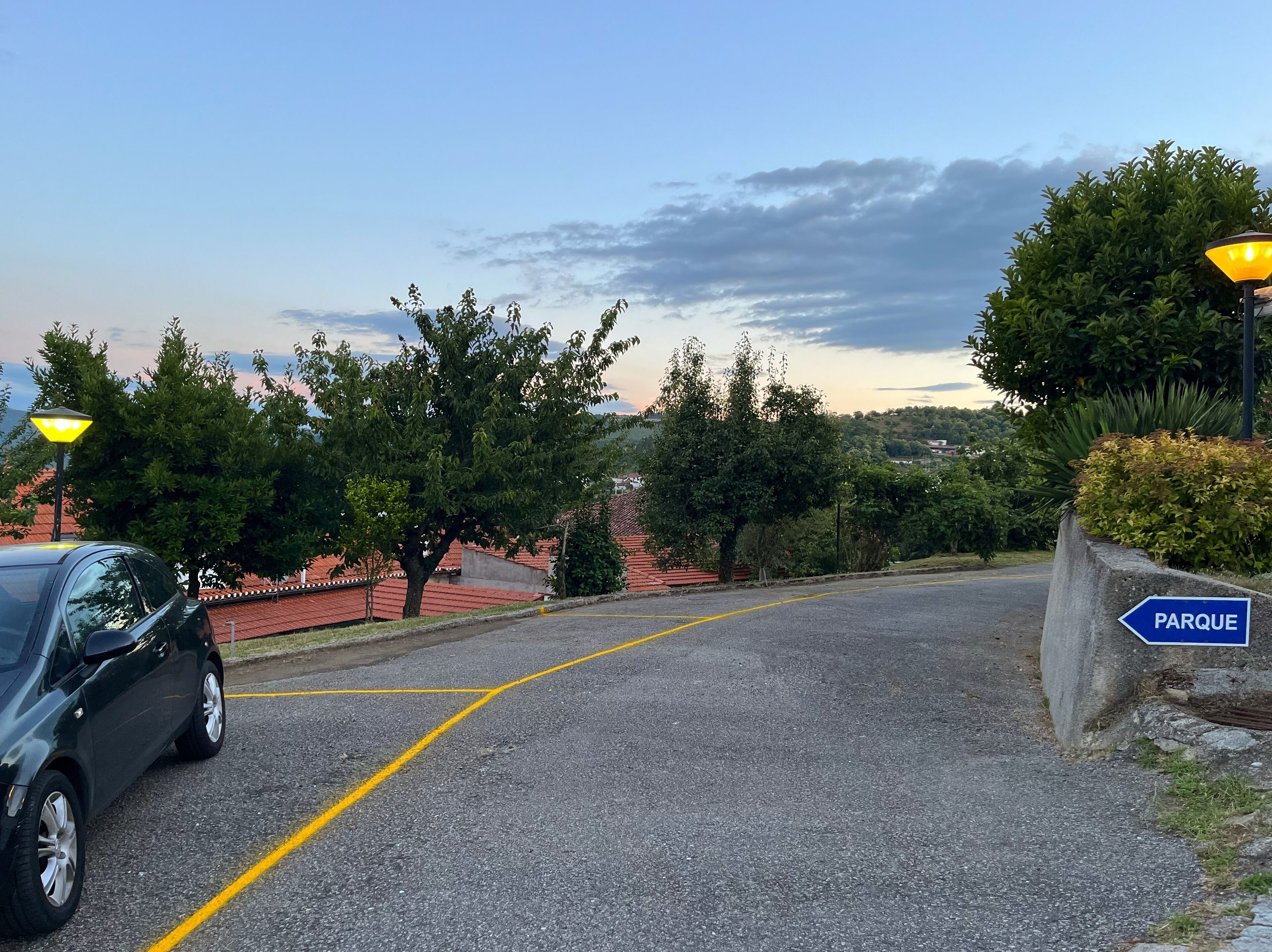 A road leading to a park with a blue sign indicating its direction.