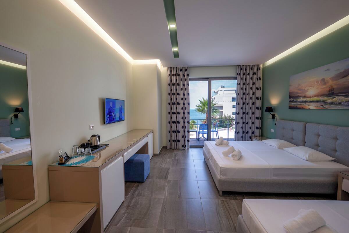 A hotel room with a bed, a desk, a chair, a TV, and a window with curtains.