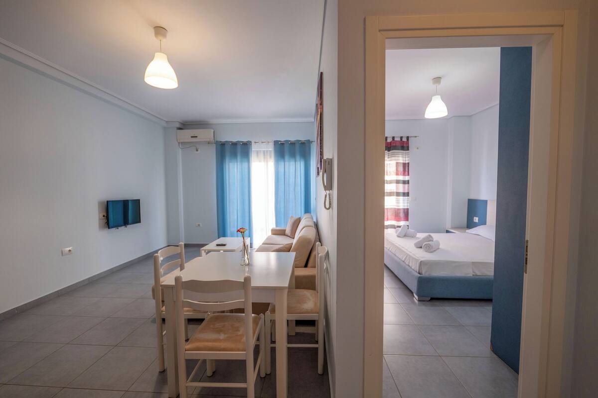 A modern hotel room with a dining area, a bed, and a TV.