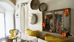 A cozy room with a bed, a chair, and a wall decorated with various items including a picture frame and a wall-mounted light fixture. - 1 Bedroom Guesthouse in Matera (Matera)