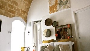 A bedroom with a bed, a mirror, a wall clock, and a door. - 1 Bedroom Guesthouse in Matera (Matera)