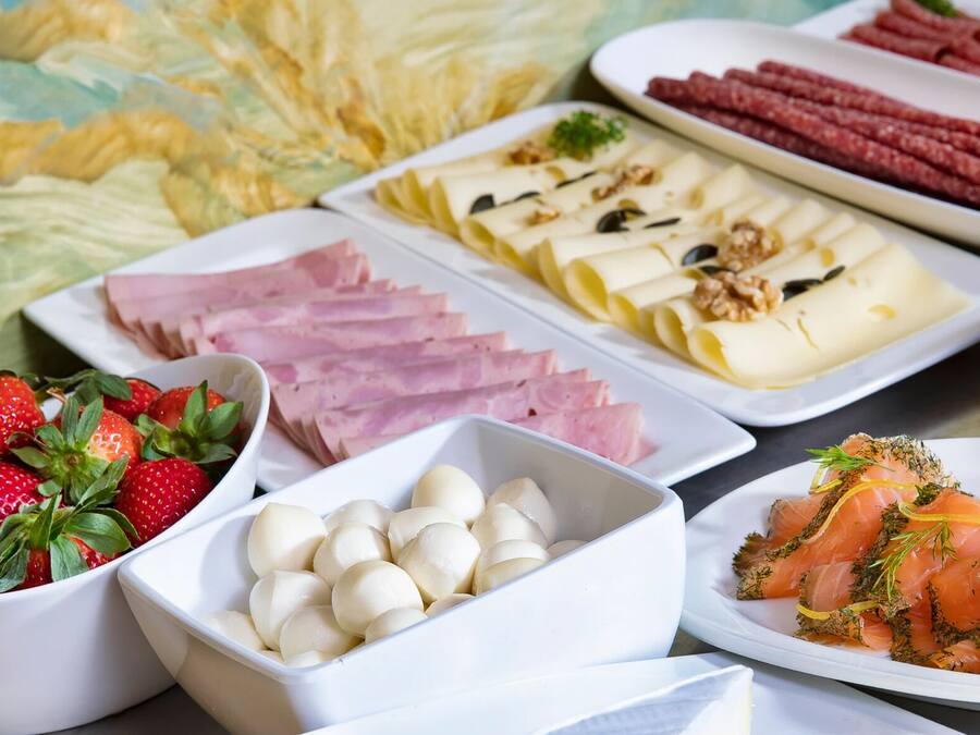 A variety of food items including strawberries, ham, cheese, and smoked salmon on a table.
