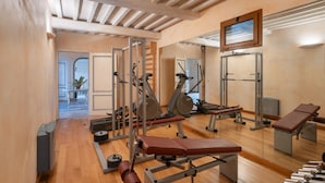 A gym with exercise equipment, wooden floors, and a large mirror. - Villa Monte Bottigli (Grosseto)