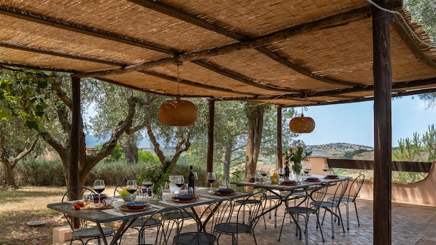 An outdoor dining area with tables and chairs, surrounded by trees and a view of the countryside. - Villa Monte Bottigli (Grosseto)