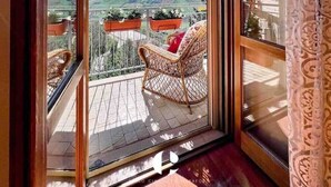 Un balcon agrémenté d’une chaise en osier et de plantes en pot, d’où l’on peut admirer le paysage.