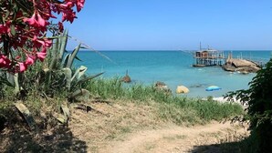 Une vue sur la côte, avec une jetée qui s’avance dans la mer, entourée de rochers et de végétation.