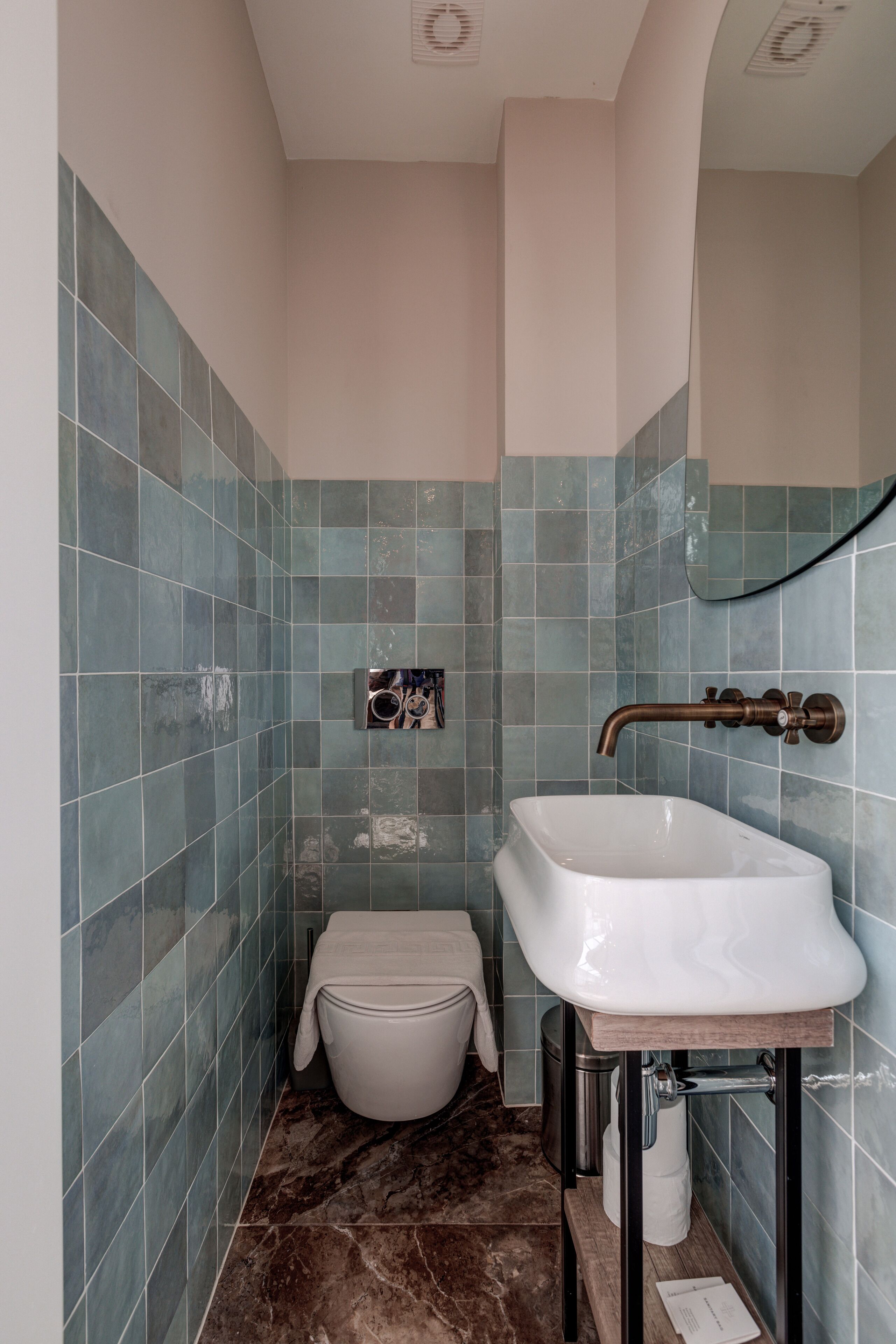 A bathroom with a white sink, a toilet, and a trash bin.