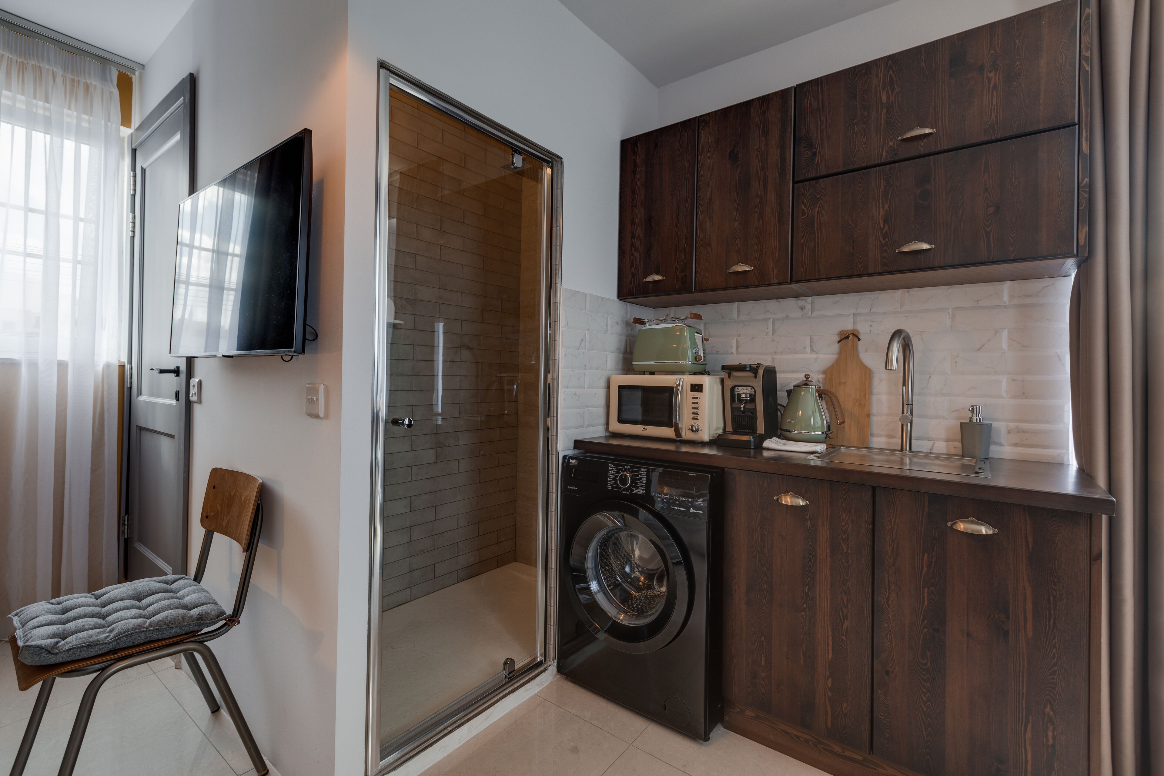 A compact kitchen with a washing machine, a microwave, and wooden cabinets.