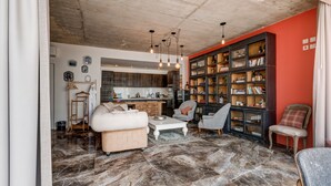 Amplia sala de estar con piso de mármol, un sofá blanco, una mesa de centro y una estantería llena de libros.
