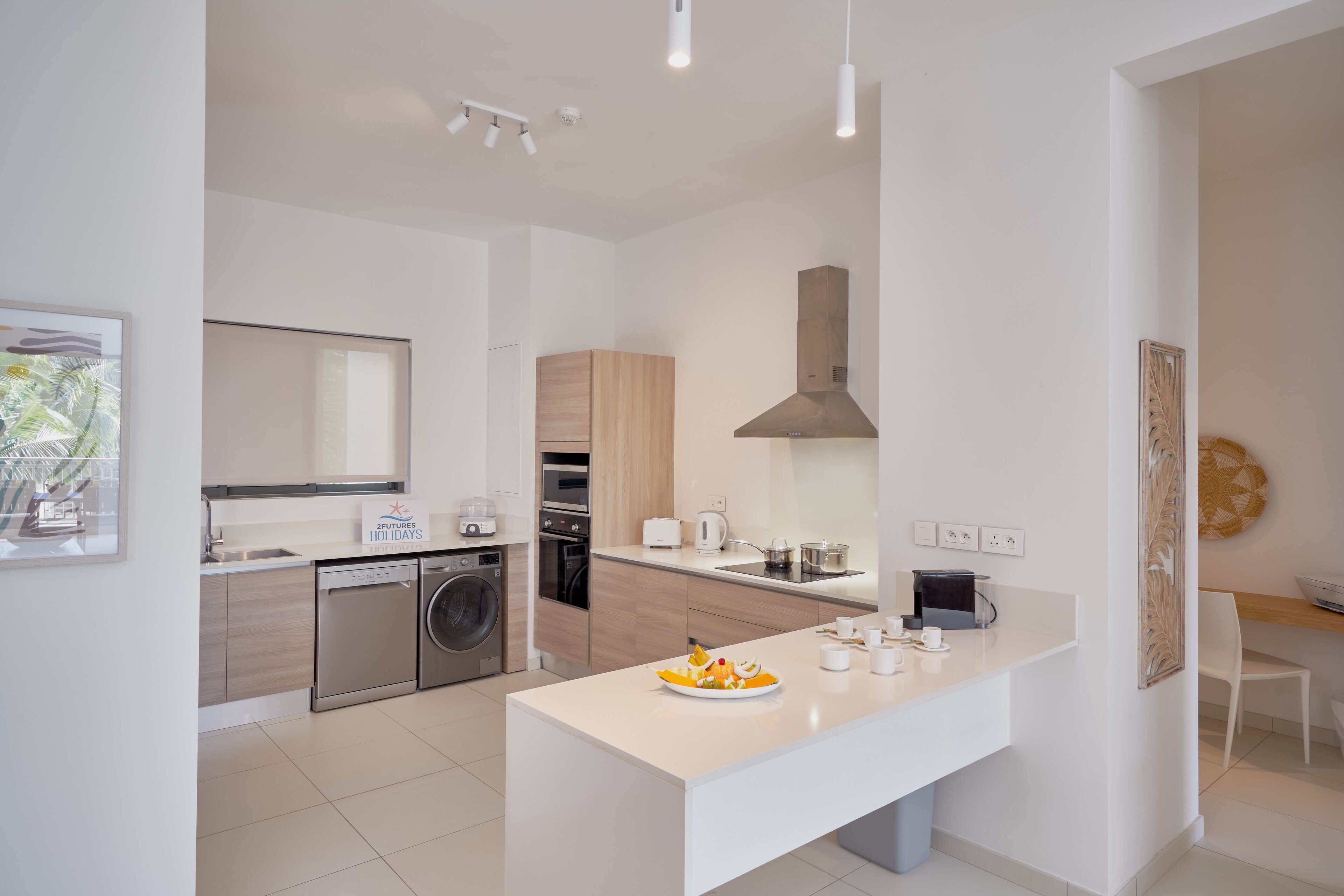 A modern kitchen with a central island, built-in appliances, and a dining area with a white table and chairs.