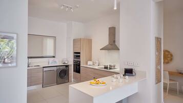 A modern kitchen with a central island, built-in appliances, and a dining area with a white table and chairs.