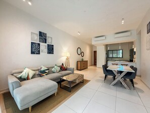 Uma sala de estar moderna com sofá, mesa de centro e área de jantar com cadeiras.