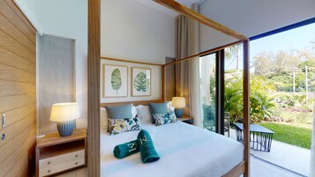 Habitación de hotel moderna con una cama grande, dos mesitas de noche con lámparas, vistas a un jardín a través de ventanas de techo a suelo y obras de arte en las paredes.