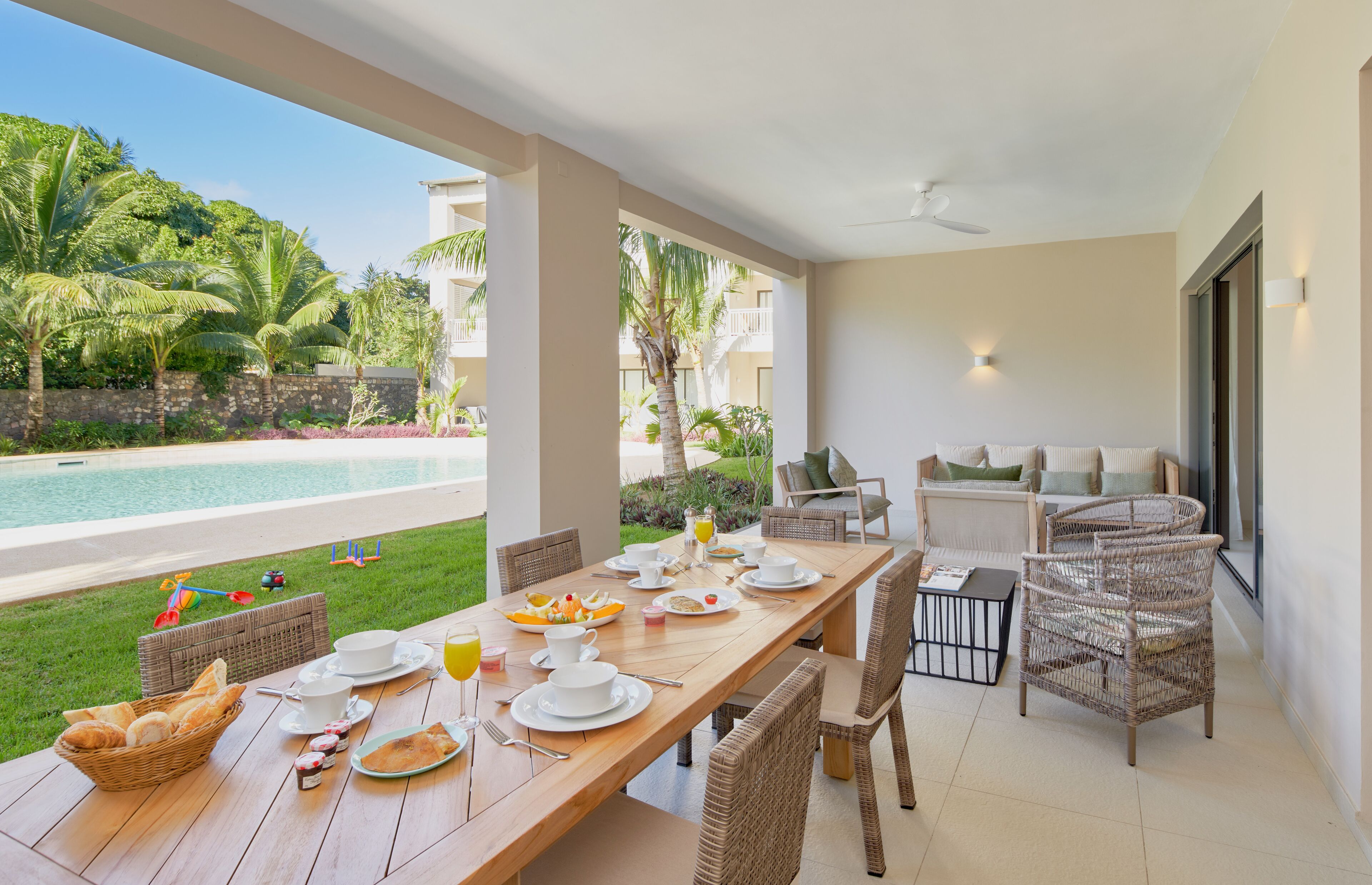 A dining area with a pool view, wicker furniture, and breakfast setup.