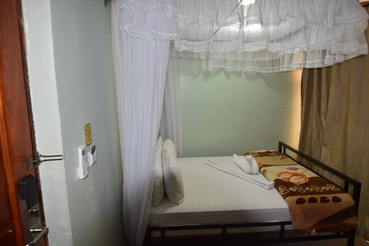 Ein Einzelbett mit Baldachin, einem Nachttischtelefon und einer Tagesdecke mit Blumenmuster.