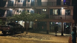 Een meerlaags hotel met balkons en een bord waarop staat 