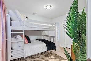 A bunk bed room with a white ceiling, a zebra-patterned rug, and a large green plant. - Modern Clearwater Beach House, Heated Pool, Golf! (Seminole)