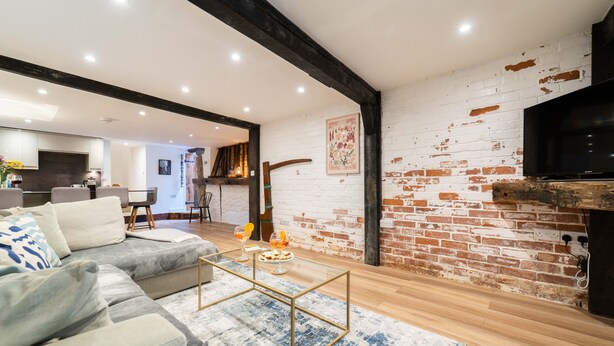 A modern living room with a sectional sofa, a glass coffee table, and a brick wall. - The Boathouse, St Ives – Sleeps 4 – Dog-Friendly (St Ives)
