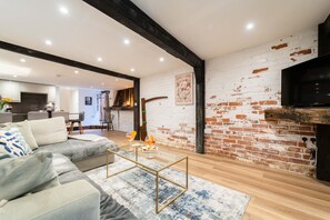 Una sala de estar moderna con un sofá modular, una mesa de centro de vidrio y una pared de ladrillo.