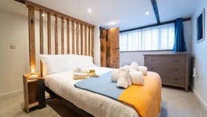 A bedroom with a bed, bedside table, dresser, and a window with blinds. - The Boathouse, St Ives – Sleeps 4 – Dog-Friendly (St Ives)