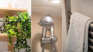 A bathroom with a shower, a towel rack, and a shelf with a plant. - Little Waves, St Ives – Sleeps 2 – Courtyard - Garage Parking (St Ives)