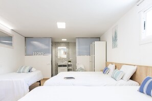 Un dormitorio moderno con dos camas individuales, un espejo grande, un armario y un baño con ducha y lavamanos.