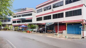 A two-story building with a red and white facade, a blue garage door, and a small outdoor seating area with a blue canopy. - Hotel O Bagus Stay (Tanjung Pinang)