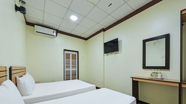 A hotel room with two beds, a desk with a mirror, a television, and an air conditioning unit. - Hotel O Bagus Stay (Tanjung Pinang)