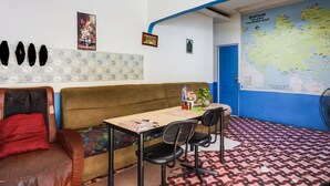 A room with a brown sofa, a table with chairs, a map on the wall, and a patterned floor. - Hotel O Bagus Stay (Tanjung Pinang)