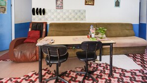 A room with a brown sofa, a small table, two black chairs, a red pillow, and a patterned rug. - Hotel O Bagus Stay (Tanjung Pinang)