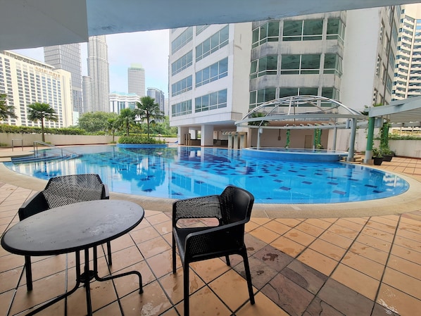 An indoor swimming pool with tiled flooring and two black chairs.