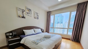 A modern hotel room with a large bed, wooden floor, and a city view through the window. - Crest Residence Klcc  (Kuala Lumpur)