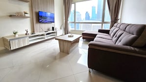 A modern living room with a flat-screen TV, a sofa, a coffee table, and a city view through large windows. - Crest Residence Klcc  (Kuala Lumpur)