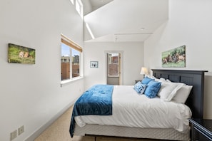 Une chambre à coucher avec un lit, une fenêtre et deux tableaux accrochés au mur.