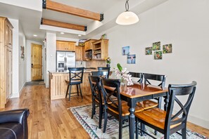 Une cuisine moderne avec des meubles en bois, un îlot central et un coin repas comprenant une table et des chaises en bois.