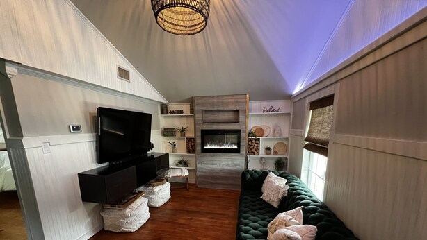 Ein modernes Wohnzimmer mit einem dunkelgrünen Sofa, einem Flachbildfernseher, Holzböden und einem Kamin.