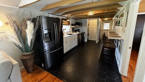 Eine moderne Küche mit einem schwarzen Kühlschrank, weißen Schränken und einem Boden mit sechseckigen Fliesen.