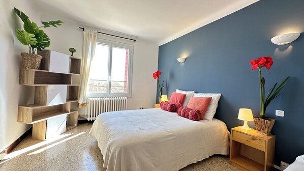 Ein Schlafzimmer mit Bett, Nachttischen, einem Fenster und einem Wandregal.