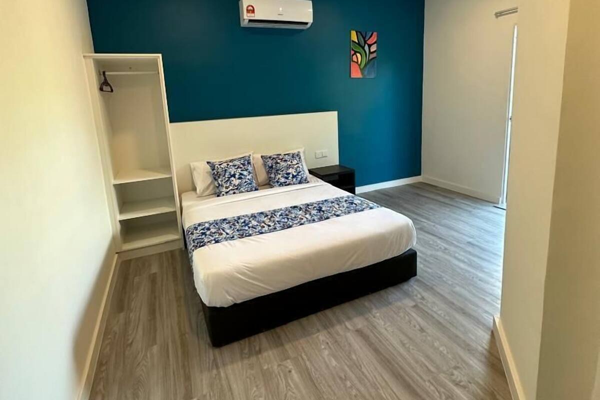 Een slaapkamer met een bed, een garderobe, een wandairconditioner en kleurrijke kunst.