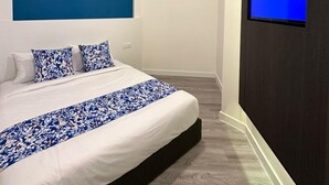Camera da letto moderna con un letto grande, una parete azzurra a contrasto, una TV a parete e un quadro con un cielo stellato.
