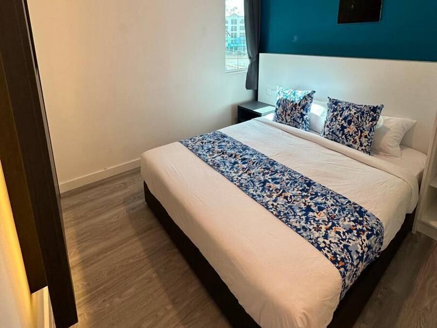 Habitación de hotel moderna con una cama grande, una mesita de noche, un ventanal con cortinas y una pared azul de acento.