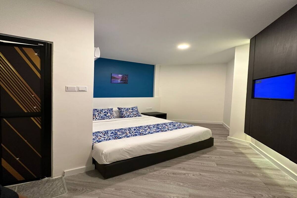 Een moderne hotelkamer met een groot bed, een flatscreen televisie en een blauwe accentmuur.