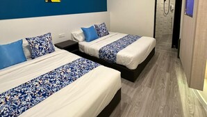 Camera d'albergo moderna con due letti, una parete decorata in blu e un angolo doccia.