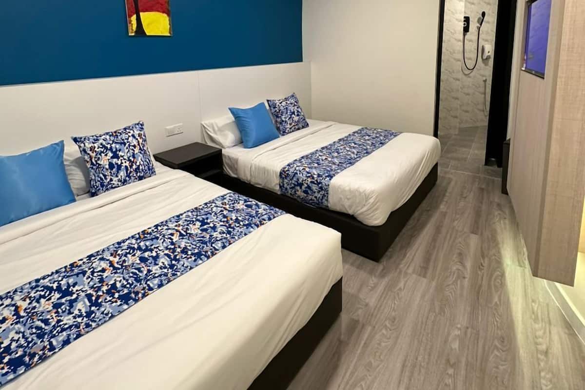 Een moderne hotelkamer met twee bedden, een blauwe accentmuur en een douche.