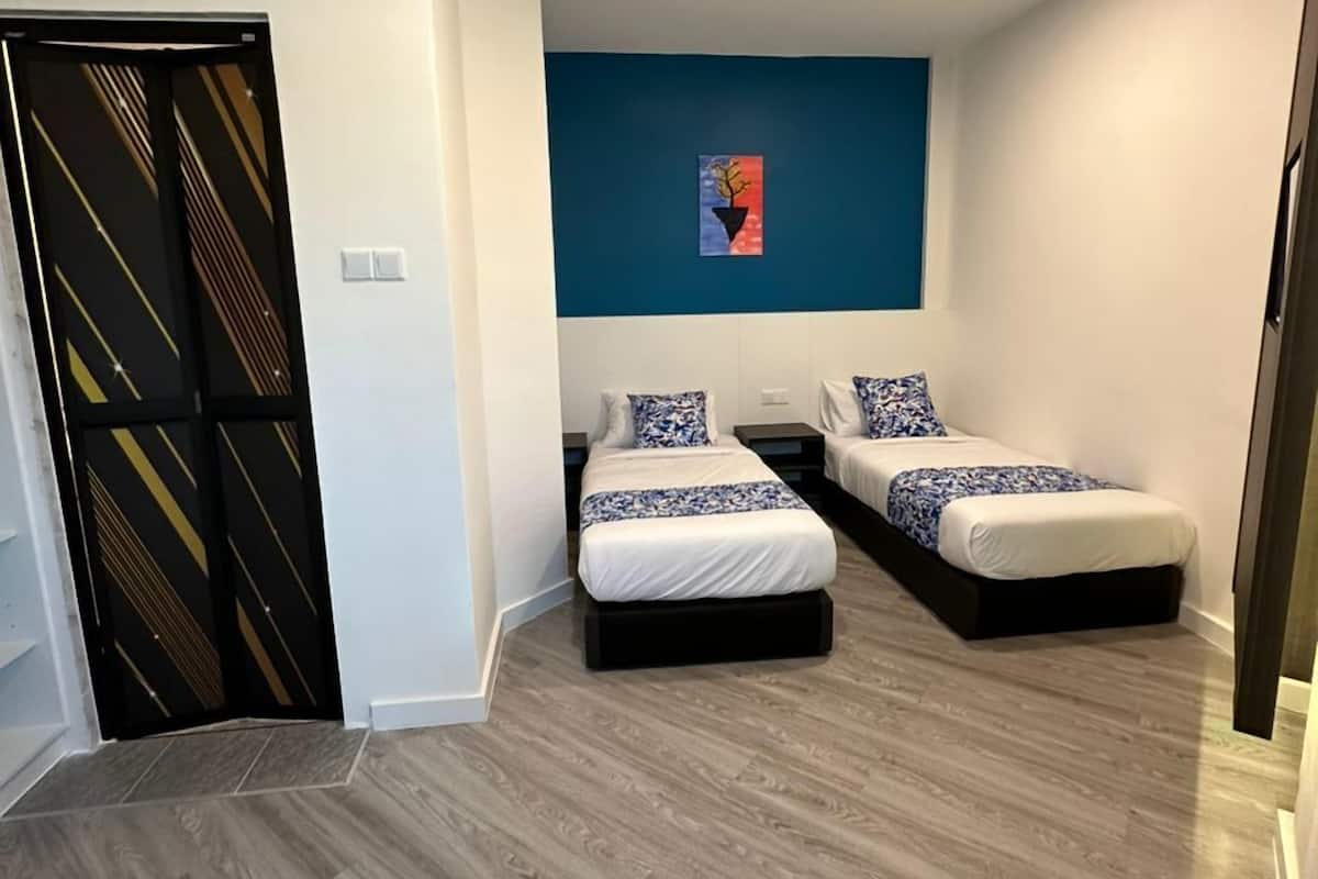 Een slaapkamer met twee bedden, een blauwe accentmuur en een deur met een geometrisch patroon.