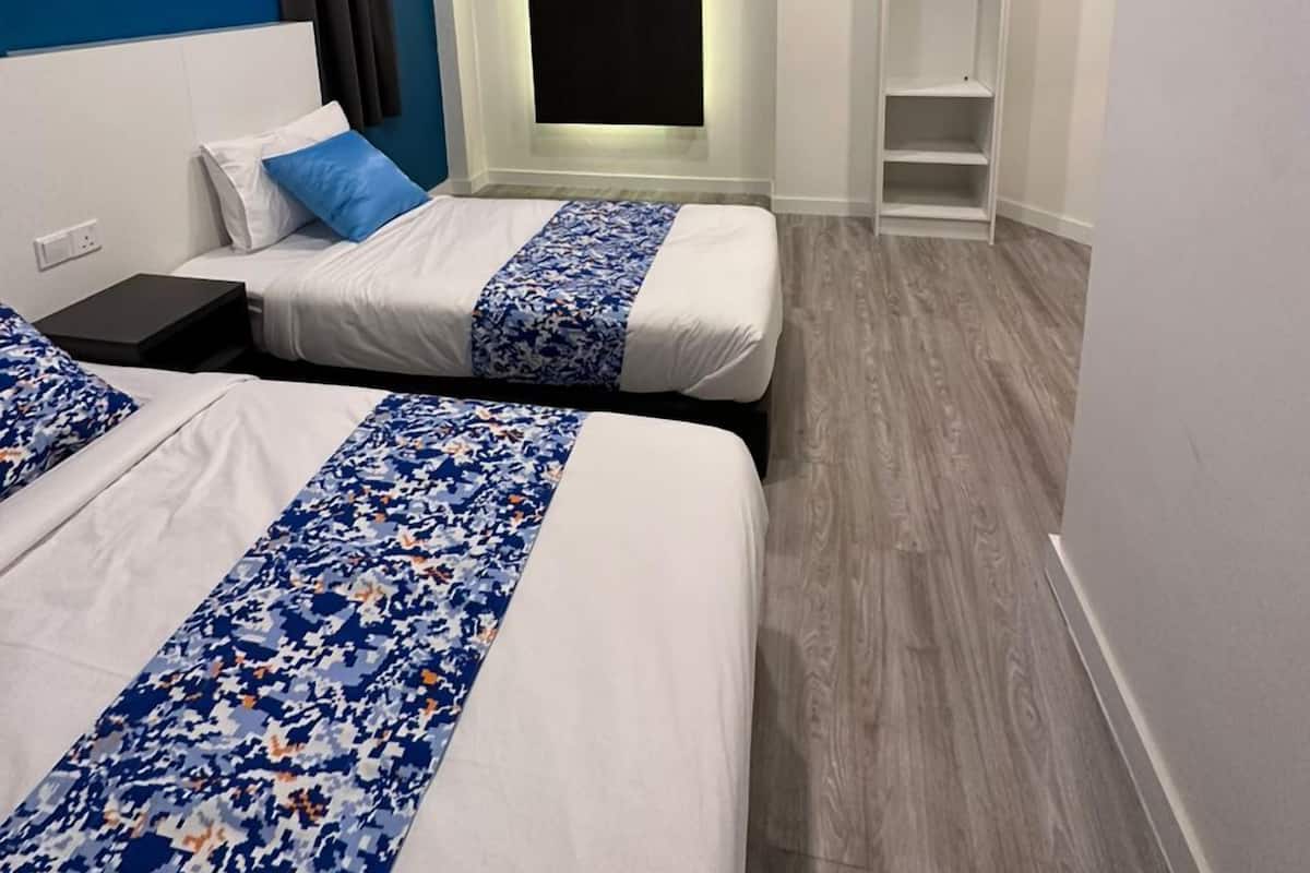 Een hotelkamer met twee bedden, een aan de muur bevestigde televisie, een kledingkast en een plankunit.